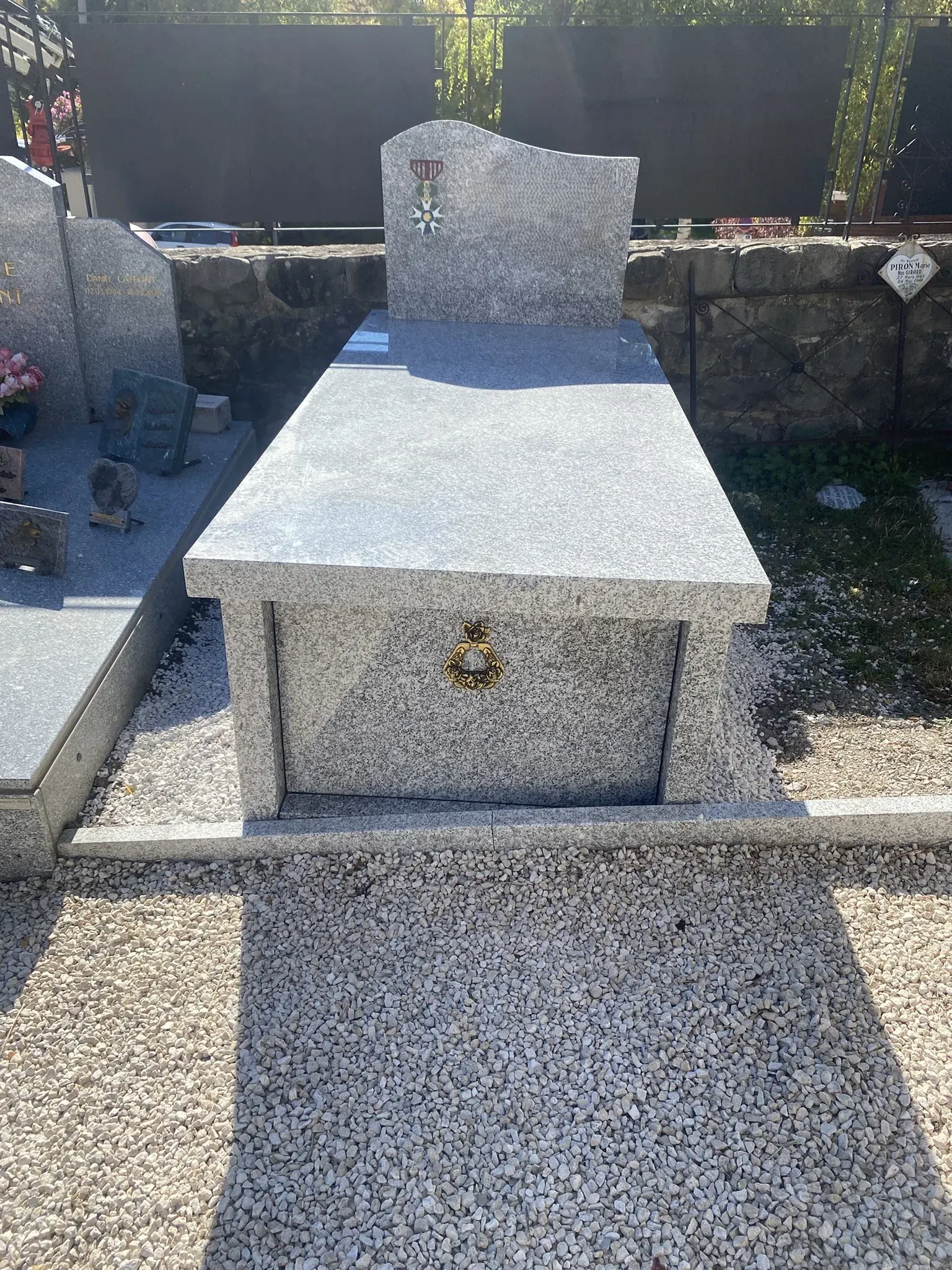 Tombeau individuel en granit gris clair avec une gravure de décoration militaire.