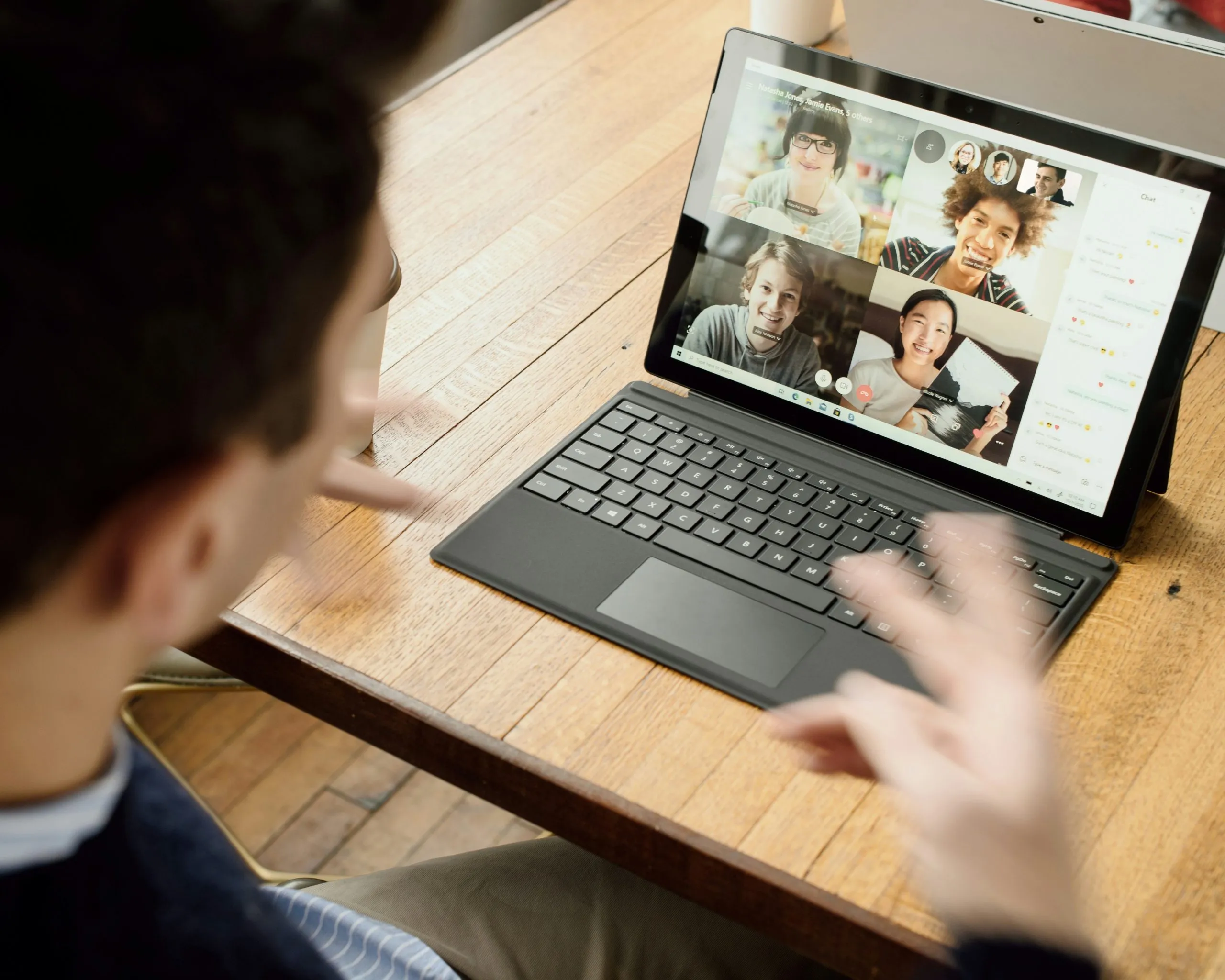 Personne participant à une visioconférence de groupe sur une tablette tactile avec clavier.